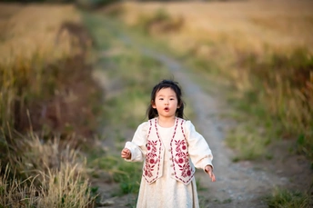 一个小女孩穿着白色裙子走在田间的路上