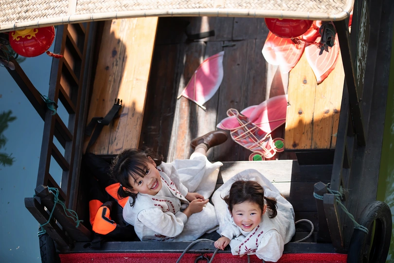两个小女孩坐在一个小手推车上 车上有洋娃娃。