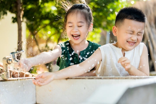 一个年轻男孩和一个小女孩在有流动水的洗碗池里洗手
