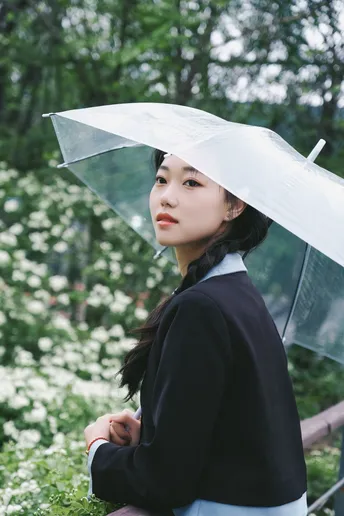 一位女士手持透明雨伞站在雨中
