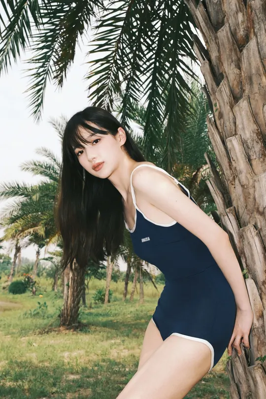 一位穿着黑色衣服的年轻女子靠在一棵棕榈树上