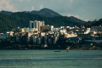 城市前方有一大片水域 山丘上有建筑物 海洋中有一艘船。