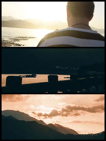 一张男子坐在长凳上 眺望着水面 湖泊和山脉 当太阳落山时