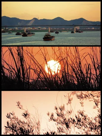 夕阳下的一张照片 背景是一片水域 有一些船和山峦。