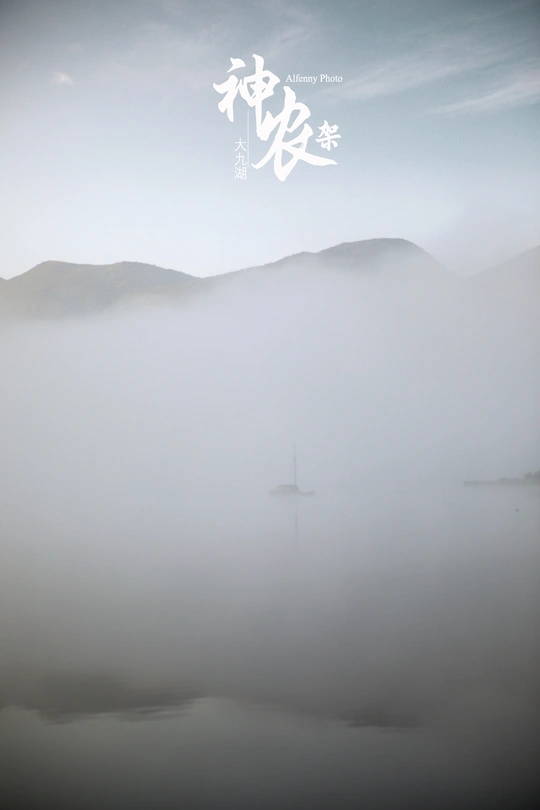 雾蒙蒙的早晨 水面上有一艘帆船 群山笼罩在雾中