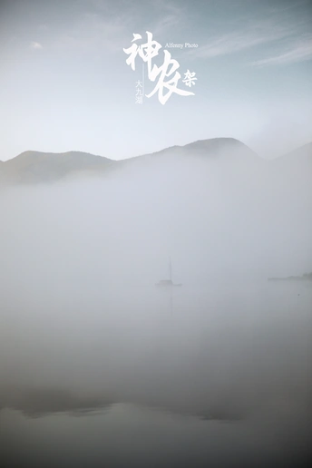 雾蒙蒙的早晨 水面上有一艘帆船 群山笼罩在雾中