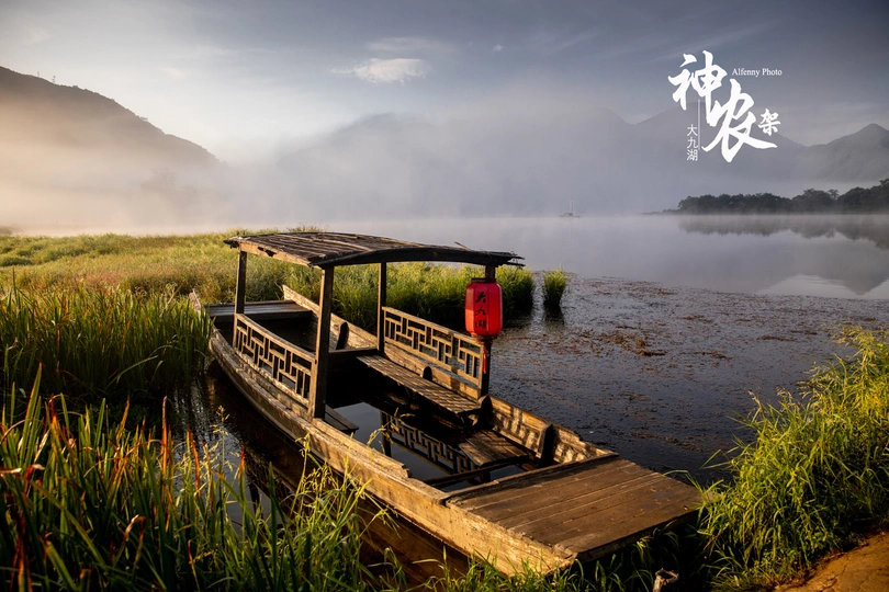 一艘老船停在湖中的一个小码头上 背景是雾覆盖的山脉