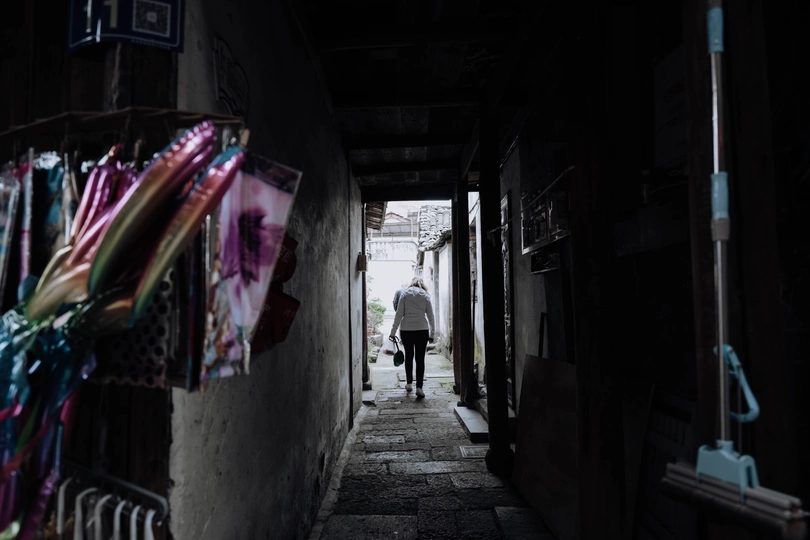 一个黑暗的巷子 晾衣绳沿着建筑物的侧面晾晒 一个人在狭窄的走廊里走。