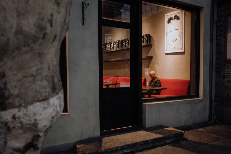 一个坐在红色沙发上的男人 在一个有门和窗户的房间里