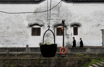 一座带有白色墙壁和窗户 人们经过的建筑