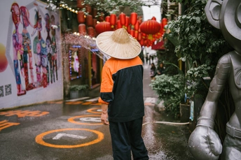 一个人戴着橙色帽子 拿着雨伞走在大街上
