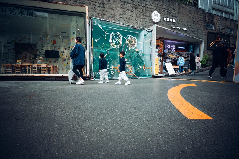 一个男子走在街上 孩子们在商店前面的道路上玩耍。