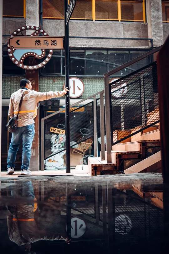 一个站在积水潭前与建筑物对话的男子 手中拿着雨伞