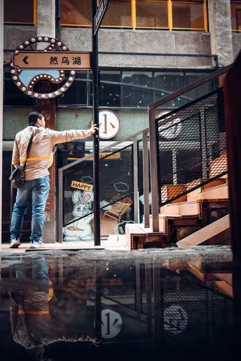 一个站在积水潭前与建筑物对话的男子 手中拿着雨伞