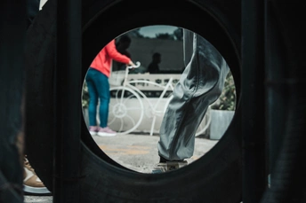 一个圆镜 中间站着一个人 背景中有一位女士骑着白色自行车。