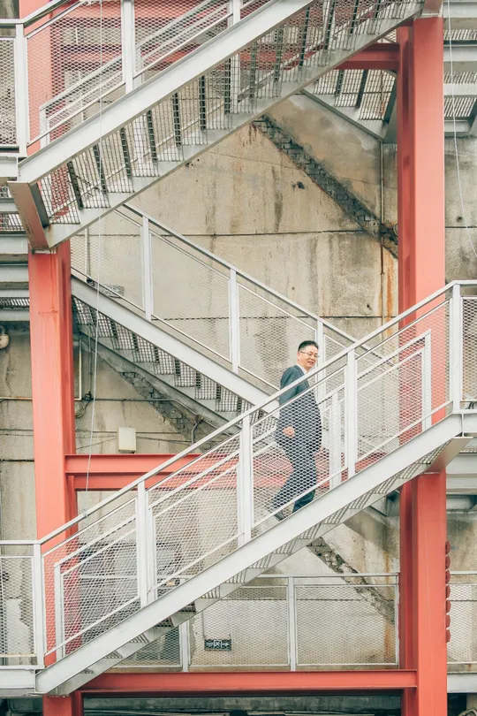 站在一栋楼前的红色楼梯上的一个男人