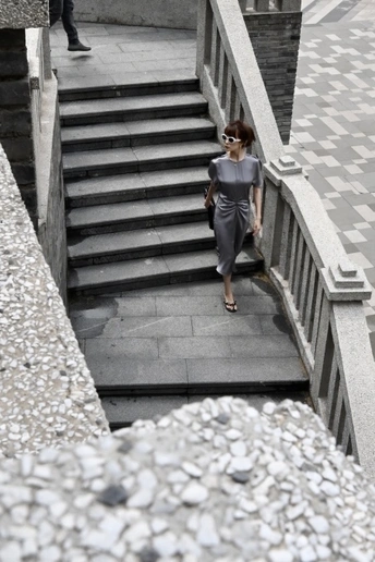 一位穿着黑色连衣裙的女人正在走上一些楼梯。