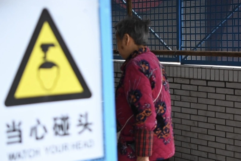 站在墙边有警告标志的女子和经过的男子