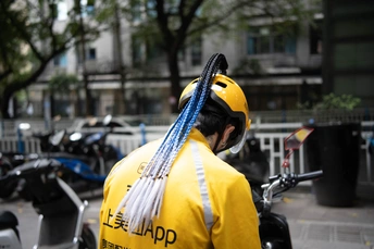 一个戴黄夹克和头盔坐在滑板上的男人