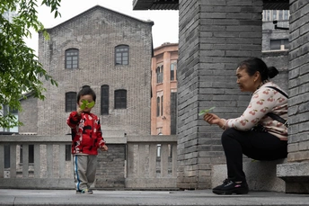 一个戴花的年轻女孩坐在街边一栋建筑前