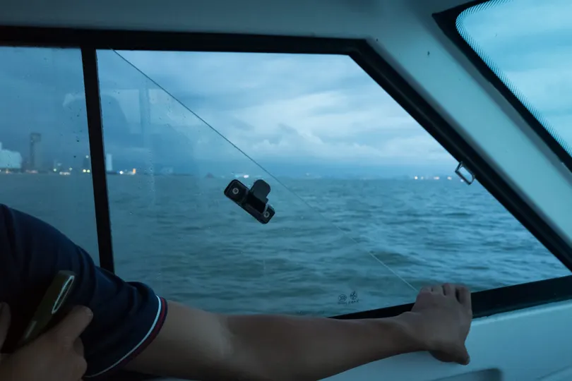 一个人在海洋上驾驶帆船 双脚站在桥上。