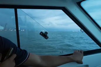 一个人在海洋上驾驶帆船 双脚站在桥上。