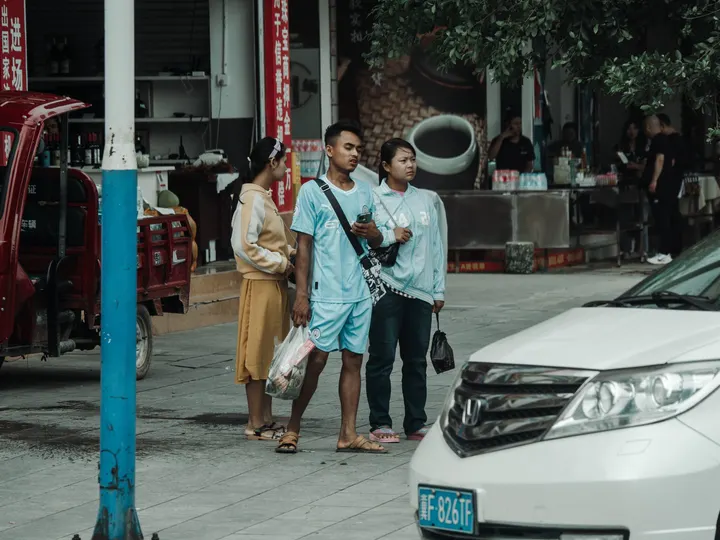 一些人在人行道上站在一些汽车旁边