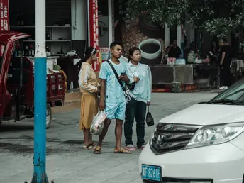 一些人在人行道上站在一些汽车旁边