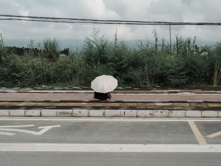 一个人拿着白伞穿越空荡荡的街道