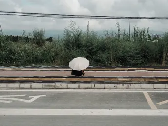 一个人拿着白伞穿越空荡荡的街道