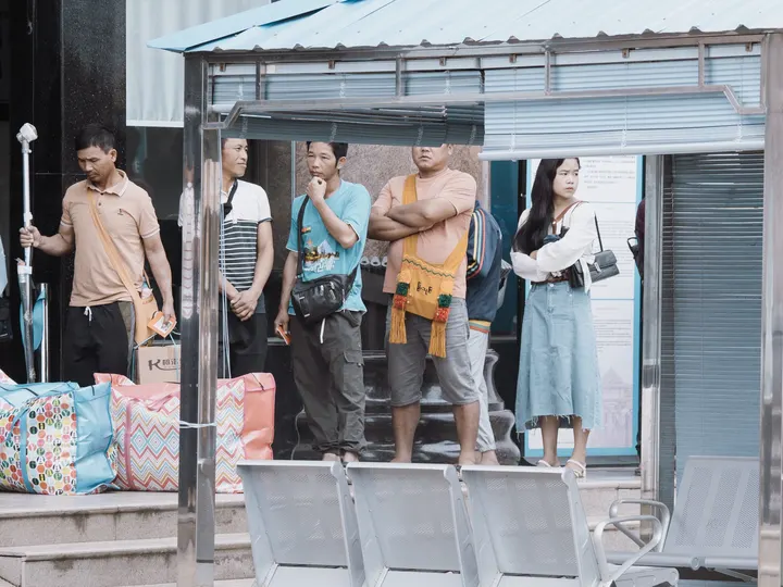 几个人走在一个公交车站附近的人行道