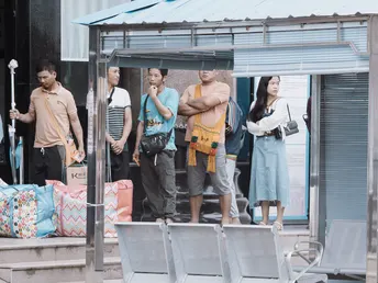 几个人走在一个公交车站附近的人行道