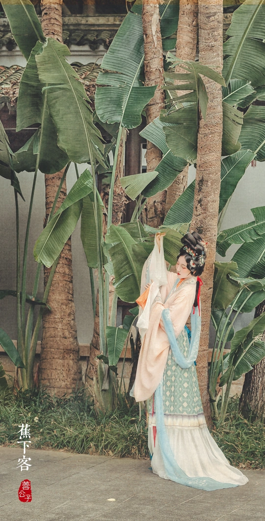 一位穿着裙子的女人雕像站在一丛香蕉树前