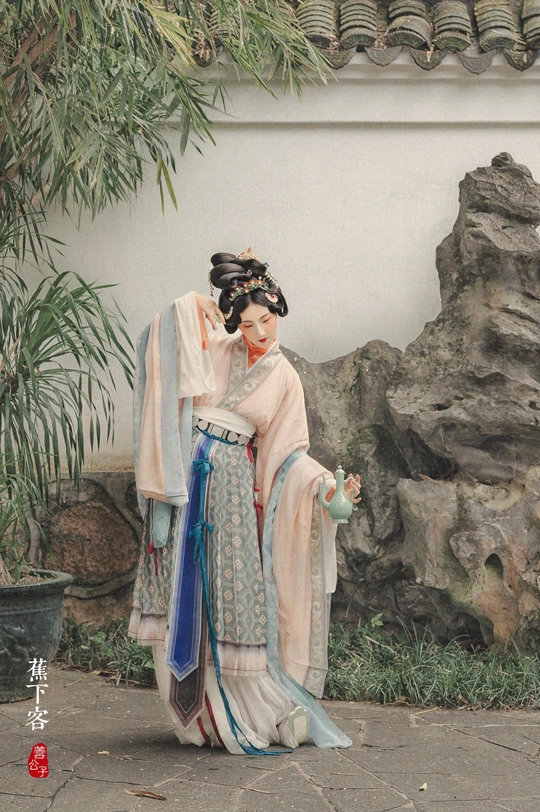 一位穿着costume的女士站在一位拿着伞的女人雕像旁边