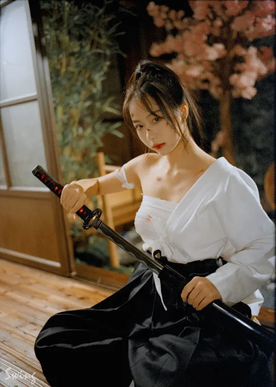 一位穿着白色和服的年轻女子 手里拿着一把黑色雨伞。