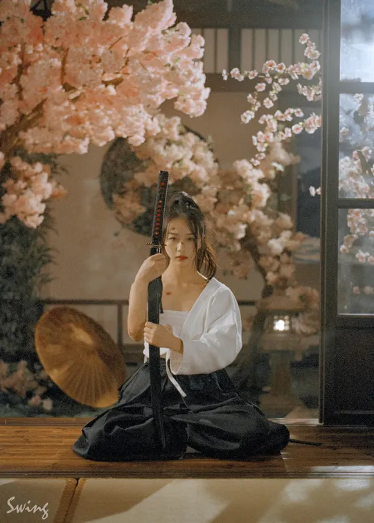 一个穿着白色和服的女人拿着雨伞坐在地板上