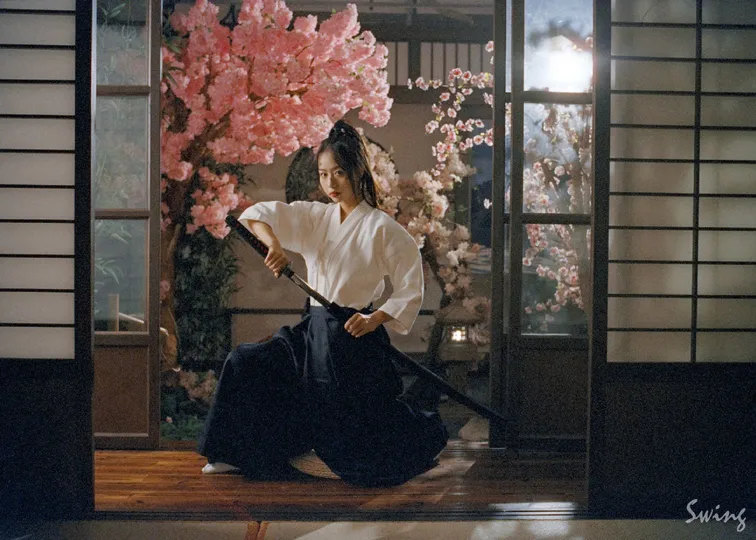 一位跪在樱花树下的穿着白色和服的女人