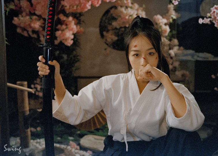 一位年轻女子手持网球拍 手拿白色雨伞进行姿势摆拍。