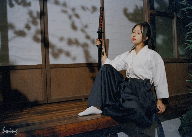 一个穿着白色和服的年轻女子拿着网球拍坐在房子的前廊上