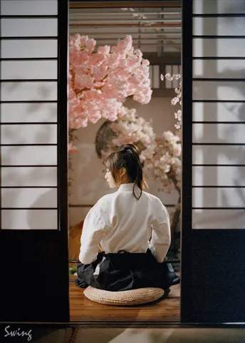 在门口前地板上坐着一个穿着白色和服的女人