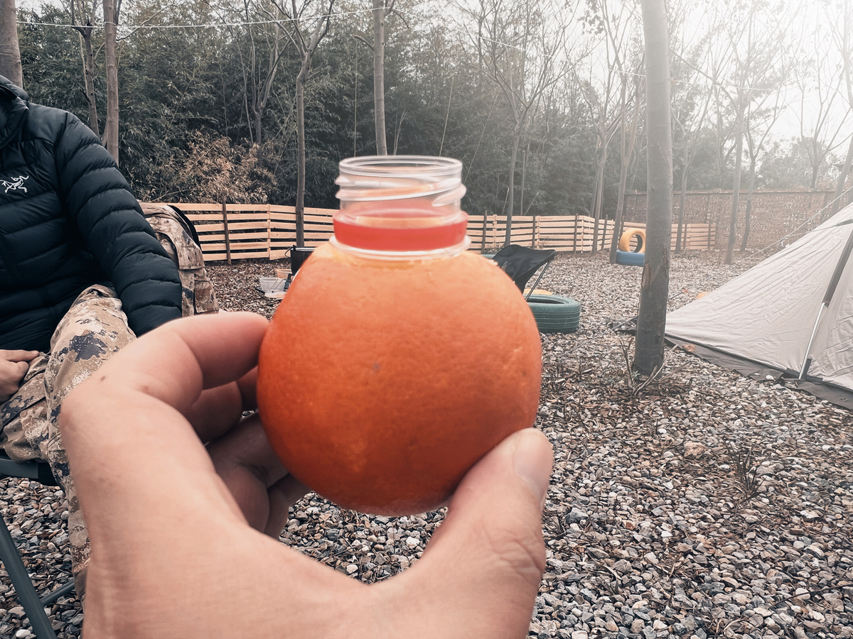 一个人手里拿着一个橙子和一个小罐子