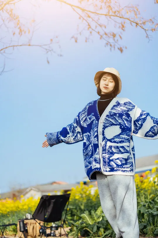 一个穿着蓝白色夹克的小男孩站在花园里