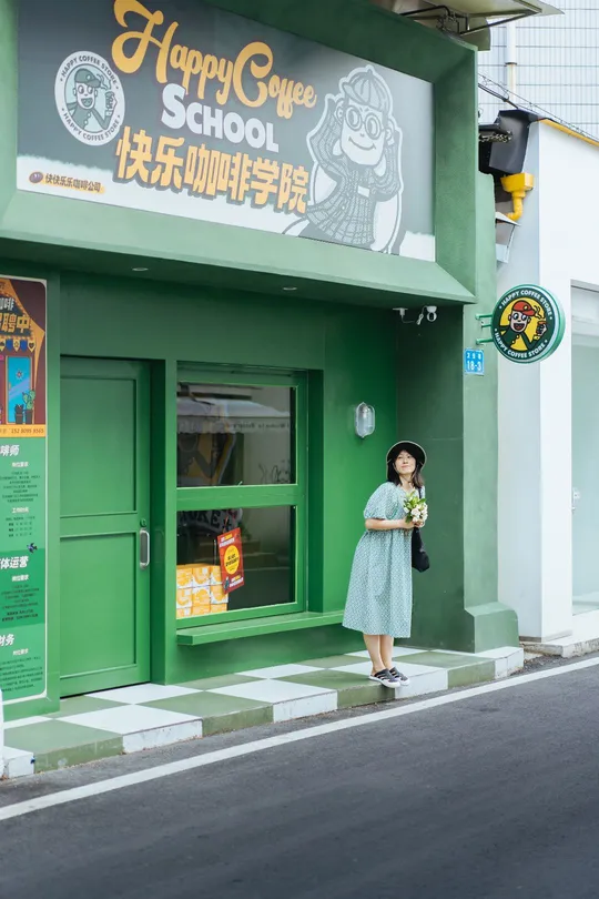 一个小女孩穿着蓝色裙子走在一条街道上 街道前面有一座绿色的建筑。