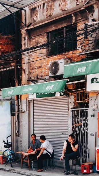 人们坐在人行道上一家餐馆外的桌子旁