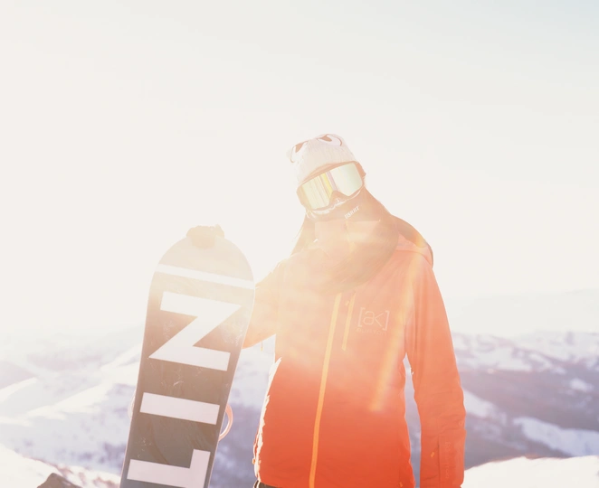 一个穿着夹克的男人 holding a snowboard standing at the top 