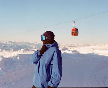 一个人穿着一件蓝色夹克站在一个雪山的顶部