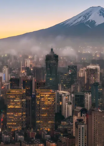 夜晚的城市 背景是山脉 城市天际线上有雾和云。