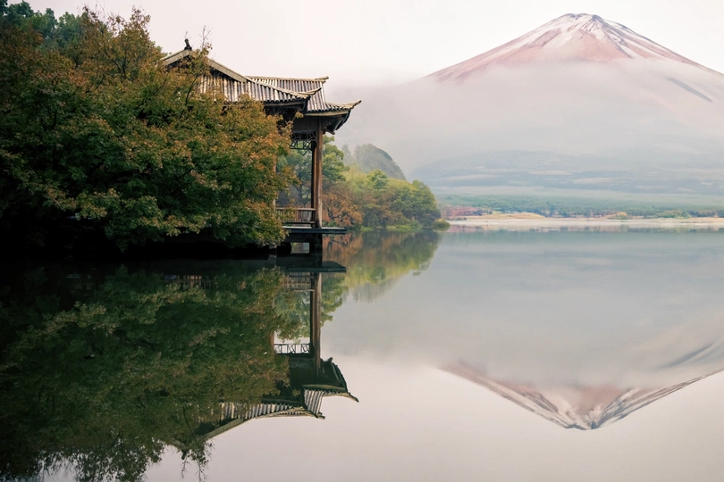 湖中倒影的山的照片 前景中有树木