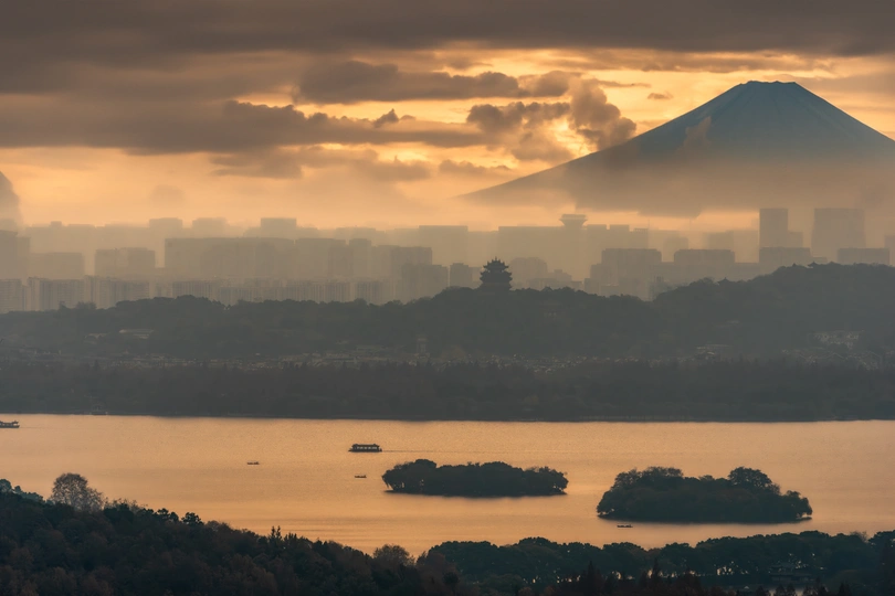 城市上空的落日 背景是山脉 前景是云朵。