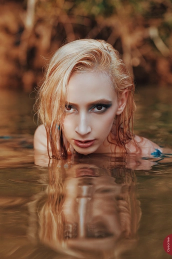 一位美丽的红发年轻女子在河里游泳的肖像